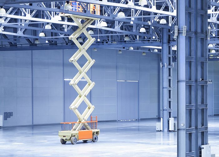 Scissor lift elevating work platform raised inside a large warehouse