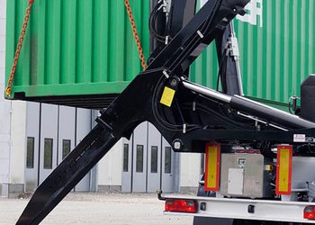 Container side lifter arm lifting a green shipping container on chains